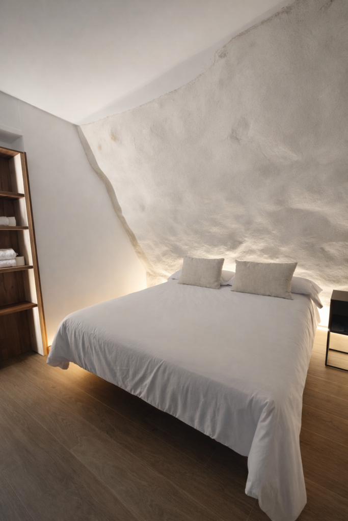 Dormitorio con pared de roca natural en casa rural Kalea Elysivm